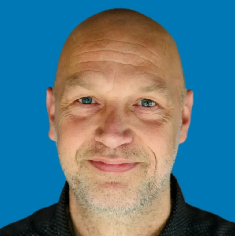 Ronald Kaal Bald man with a friendly expression and blue background.