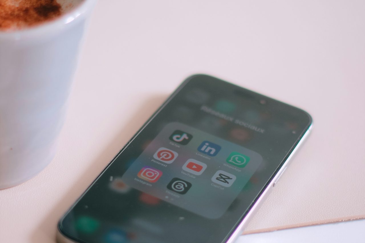 Mobiel Slimme telefoon met sociale media-apps naast een kopje koffie.